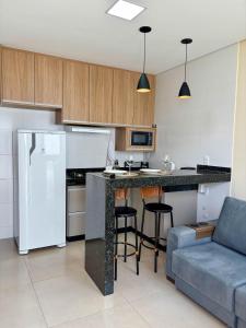 a kitchen with a refrigerator and a counter with stools at Studio Premium Araxá - Conforto, Localização e Comodidade in Araxá