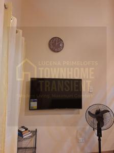 eine Uhr an einer Wand mit einem Fernseher und einem Ventilator in der Unterkunft Lucena Primeloft Townhome Transient in Lucena