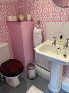 a pink bathroom with a toilet and a sink at The Old Post Office B&B in Longwitton +17 photos