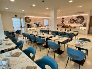 Un comedor con mesas y sillas azules. en Hotel Castiglione, en Lignano Sabbiadoro