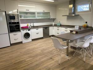 a kitchen with white cabinets and a table and chairs at Casa Kiros in Cangas de Morrazo