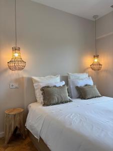 een slaapkamer met een groot wit bed en 2 verlichting bij RookieC Two Bedroom peaceful location old town AC in Cascais +21 foto's