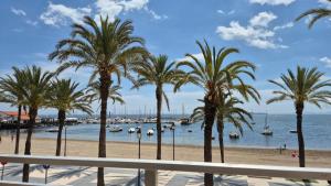 a beach with palm trees and boats in the water at Cala Serena in Los Alcázares