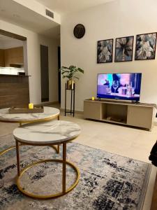 a living room with two tables and a flat screen tv at High Rise Executive Luxurious Apartments Facing Centaurus Mall - LMY Islamabad in Islamabad