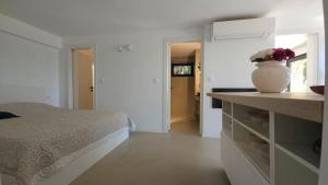 a white bedroom with a bed and a vase on a counter at Val Mar in Novi Vinodolski