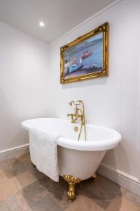 a bath tub in a bathroom with a painting on the wall at Keel Cottage & Dog Friendly in Nairn +16 photos