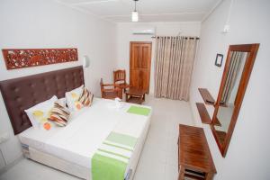 une chambre avec un lit, une chaise et un miroir dans l'établissement Royal Heritage Resort, à Kandy