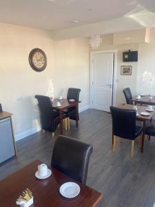 a dining room with tables and chairs and a clock on the wall at Maloney's The Square Bed & Breakfast in Charlestown