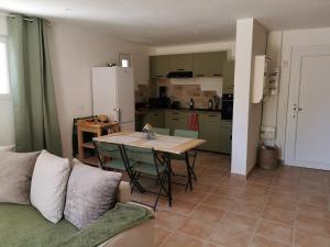 a living room with a table and a kitchen at Hébergement avec jardin in Le Garn