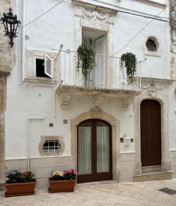 a white building with a balcony and two potted plants at 17 per 2 in Martina Franca
