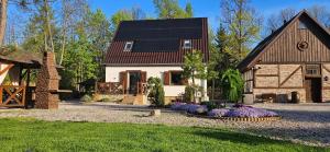 dom z czarnym dachem i ogródkiem z kwiatami w obiekcie Apartamenty Komarno 46 Jacuzzi&Sauna w mieście Komarno