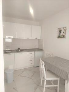 a kitchen with white cabinets and a table with a chair at Villa Dian in Neum
