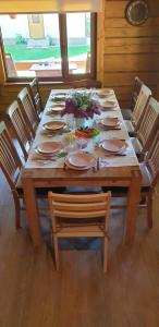 a wooden table with chairs and plates and flowers on it at Cosy VILLA with sauna in Saulkrasti