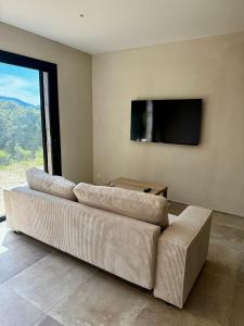 a living room with a couch and a flat screen tv at Rez-de-villa 65m2 climatisé in Propriano
