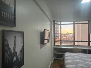 a bedroom with a bed and a window with a view at Flat mobiliado 45 - L Hirondelle in Campinas