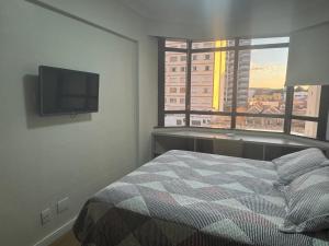 a bedroom with a bed and a flat screen tv at Flat mobiliado 45 - L Hirondelle in Campinas