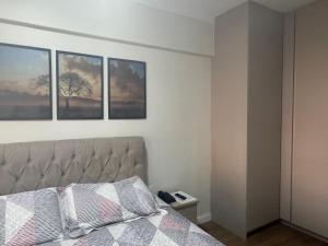 a bedroom with a bed with three pictures on the wall at Flat mobiliado 45 - L Hirondelle in Campinas