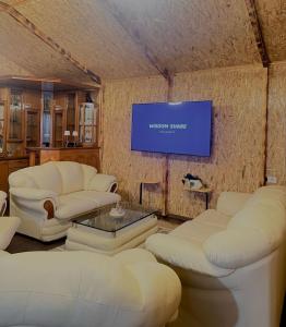 a living room with white couches and a flat screen tv at Vila Eilin - Cozy villa for perfect escapes in Tirana