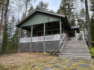 a small house with a porch and stairs in the woods at Hölmölä in Salo