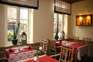 a dining room with tables and chairs and windows at Hotel Altes Stadthaus in Westerstede