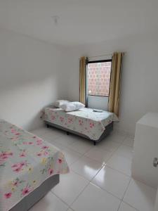two beds in a room with a window at Aconchegante Casa em Gravatá in Gravatá +20 photos