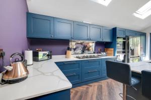 a kitchen with blue cabinets and a tea kettle on a counter at Central Windsor Luxury 3 Bedroom - Spectacular Social Kitchen and Lounge in Windsor