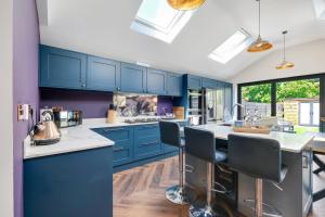 a kitchen with blue cabinets and white counter tops at Central Windsor Luxury 3 Bedroom - Spectacular Social Kitchen and Lounge in Windsor