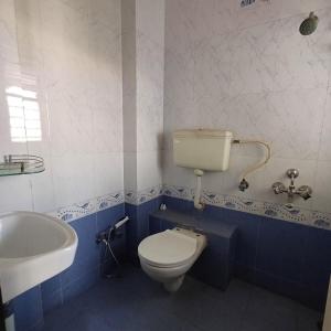 a bathroom with a white toilet and a sink at Modern Penthouse in Nature's Lap - Family Only in Nashik +18 photos