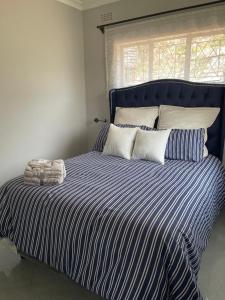 a large bed with a blue and white striped comforter at Hulley Homes- Escape to Beautiful Mountain Views in Umtali