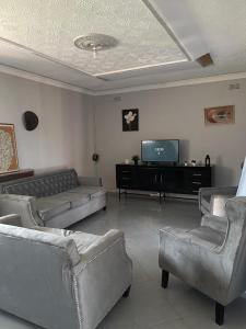 a living room with couches and a flat screen tv at Hulley Homes- Escape to Beautiful Mountain Views in Umtali