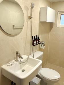une salle de bain avec un lavabo, des toilettes et un miroir dans l'établissement 'SUPUL HOUSE' Danggok Station 10 minutes, Free late checkout, à Séoul