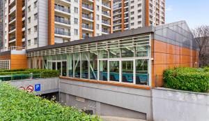 a building with glass windows in front of tall buildings at InCity Studio - Near Bucharest Mall, Balcony - RH Living in Bucharest +10 photos