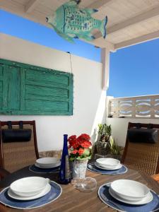a dining room table with plates and a fish on the wall at Casa Diana in Tarajalejo