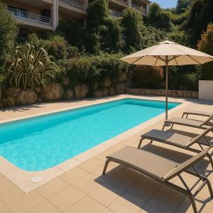 une piscine avec deux chaises et un parasol dans l'établissement Beau T3 Central - Vue mer & Piscine - A Funtana, à Propriano