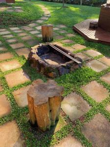 a fire pit in a garden with logs and grass at Chalé nas Nuvens - Chalé Branco in Camanducaia +1 photo