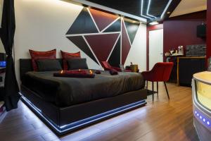a bedroom with a bed and a red chair at Redroom Spa privatif & nuit romantique à deux in Voiron