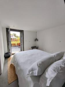 a white bedroom with a large bed and a window at Cá Por Casa Pico-Faia in Prainha de Baixo +16 photos