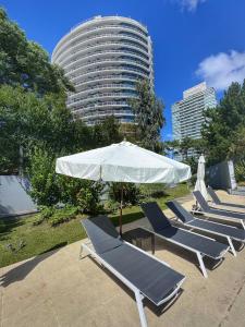 a row of lounge chairs with an umbrella and a building at Apartamentos Torre Tressesenta in Punta del Este