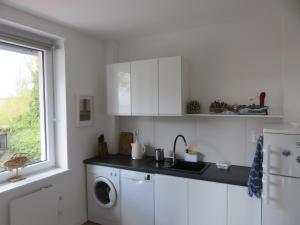 a white kitchen with a washing machine and a window at Mieszkanie Rybaka na Wiejskiej in Hel