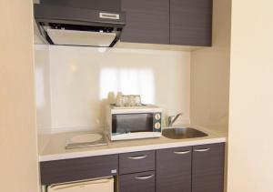 a kitchen with a microwave and a sink at Condominium Hotel Monpa in Chatan