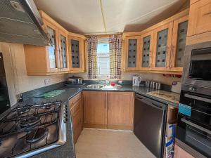 a kitchen with wooden cabinets and a stove top oven at 6 Berth Caravan For Hire With Sea Views At Haven Seashore Ref 22087A in Great Yarmouth +15 photos