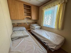 two beds in a small room with a window at 6 Berth Caravan For Hire With Sea Views At Haven Seashore Ref 22087A in Great Yarmouth