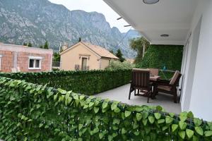 a patio with a table and chairs next to a hedge at Prcanj Seaside Heaven in Prčanj