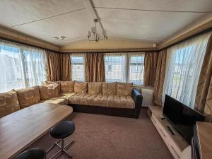 Una sala de estar con un sofá y un televisor de pantalla plana. en Lovely 8 Berth Caravan With Decking At California Cliffs In Norfolk Ref 50015J, en Great Yarmouth