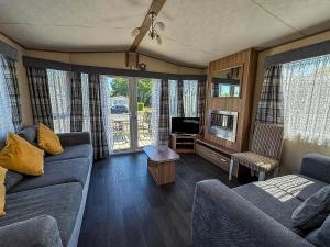 a living room with a couch and a tv at Beautiful 8 Berth Caravan At Cherry Tree Holiday Park In Norfolk Ref 70803C in Great Yarmouth