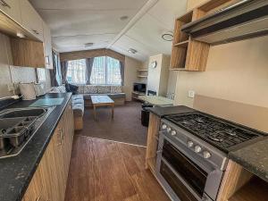 a kitchen with a stove and a living room at 8 Berth Caravan With Decking At Caister Beach In Norfolk Ref 30016S in Great Yarmouth