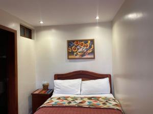 a bedroom with a bed and a painting on the wall at HOSTAL Aly 3 in Otavalo