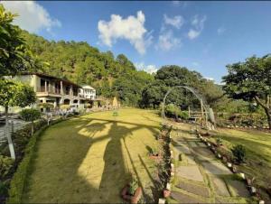 a large grass field with a shadow of a tree at KAFAL TREE Home Stay - PET FRIENDLY in Bhowāli