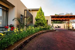 a brick walkway in front of a building with flowers at Mavuta Manor in Polokwane