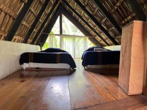 two beds in a room with a large window at Hotel La Paz in San Pablo La Laguna